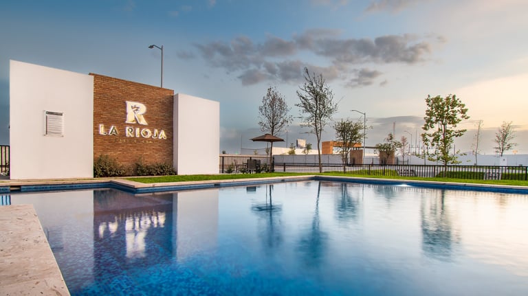 Modern building with La Rioja sign reflected in swimming pool at dusk with trees and cloudy sky